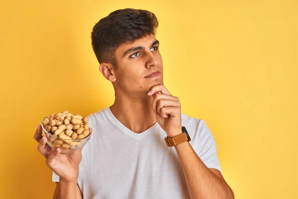 Young Indian Man Holding Bowl Peanuts Isolated Yellow Background Serious — Stock Photo, Image