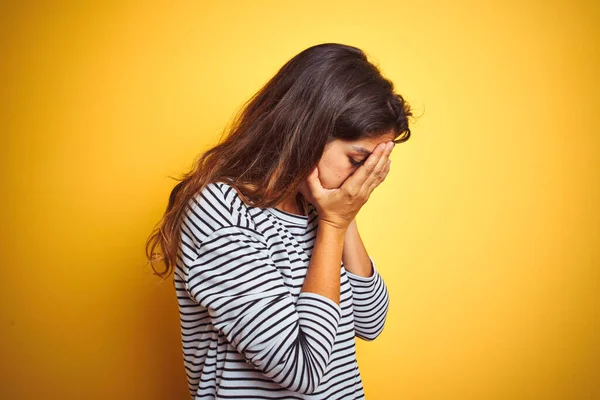 泣いている間に手で顔を覆う悲しい表情で黄色の孤立した背景の上に立つストライプのTシャツを着た若い美しい女性 うつ病の概念 — ストック写真