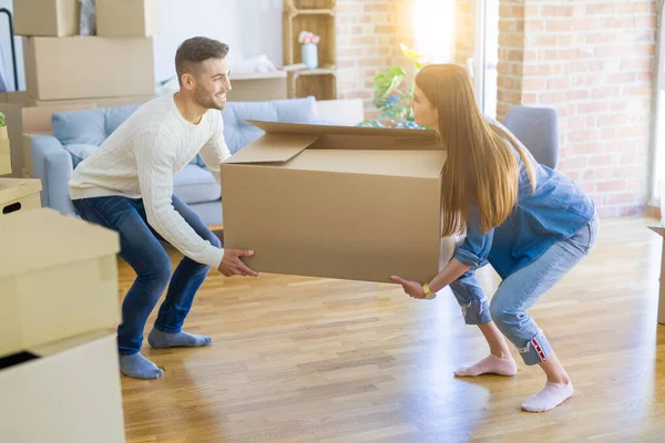 Όμορφο νεαρό ζευγάρι που κινείται σε ένα νέο σπίτι, κρατώντας μεγάλο cardboa — Φωτογραφία Αρχείου
