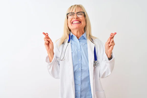 中年妇女医生 戴着眼镜和听诊器 戴着孤立的白色背景手势的手指 微笑着与希望相交 闭上眼睛 运气和迷信观念 — 图库照片