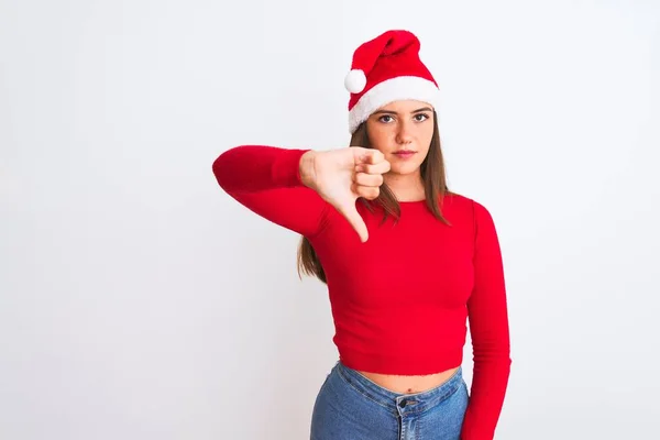 孤立した白い背景の上に立っているクリスマスサンタの帽子をかぶっている若い美しい女の子は 親指を下にジェスチャーで拒絶と否定を示す不満と怒りを見ています 悪い表現 — ストック写真