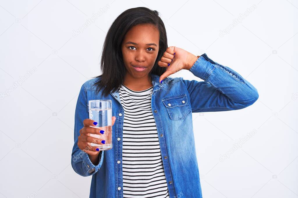 Young african american woman drinking a glass of fresh water over isolated background with angry face, negative sign showing dislike with thumbs down, rejection concept