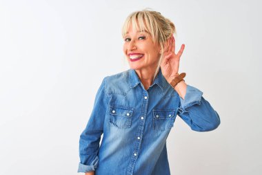 İzole edilmiş beyaz arka plan üzerinde dikilen sıradan bir kot giyen orta yaşlı kadın kulağına fısıldayarak dedikoduları ve dedikoduları dinliyor. Sağırlık kavramı.