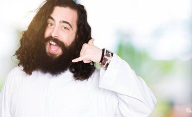 İsa Mesih kostümü giyen adam telefonda konuşmak gibi el ve parmaklarla telefon hareketi yapıyor gülümseyerek. İletişim kavramları.