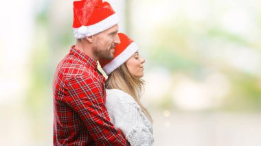 İzole arka tarafına, seyir üzerinde Noel şapka aşık genç çift dinlenmek doğal yüz emin gülümseme ile pozuyla profili.