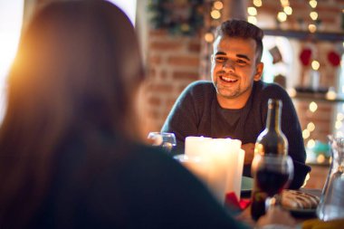 Mutlu ve kendinden emin gülümseyen genç bir çift. Evde Noel 'i kutlamak için yemek yiyorum.