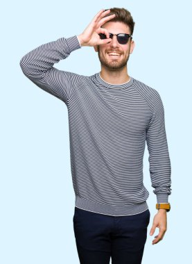 Genç yakışıklı adam giyen güneş gözlüğü el gülümseyen, ok jest yapıyor göz parmakları ile mutlu yüz üzerinden seyir.