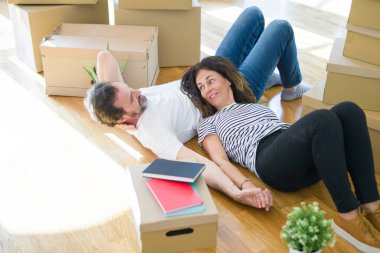 Orta yaş Senior romantik çift yerde yatıyor, yeni bir eve hareket için mutlu gülümseyen, rahatlatıcı ve ambalaj kutularının bir mola alarak