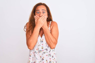 Orta yaşlı olgun bir kadın beyaz arka planda dikiliyor. Ağzını yanlışlıkla ellerinle kapatıyor. Gizli konsept.