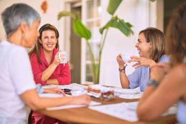 Genç ve güzel bir kız mutlu ve kendinden emin bir şekilde terasta oturmuş bir fincan kahve içiyor.