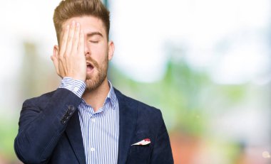 Genç yakışıklı bussines adam yarım yüz, göz ve ağız el ile kapsayan yorgun esneme. Acı yüzü acıyor.