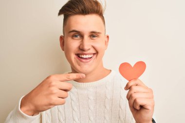 Genç, yakışıklı, romantik bir adam. Elinde kağıt kalpler var. İzole edilmiş beyaz arka planda duruyor.
