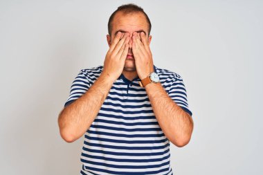 İzole edilmiş beyaz arka planda duran sıradan çizgili polo giyen genç adam yorgunluk ve baş ağrısı için gözlerini ovuşturuyor, uykulu ve yorgun ifade. Görüş sorunu