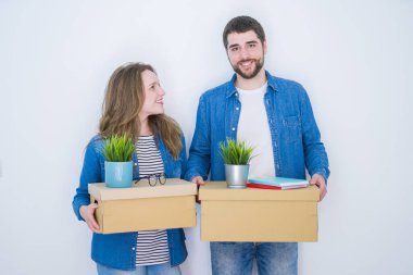 Beyaz izole arka plan üzerinde yeni bir eve taşımak için çok mutlu karton kutuları tutan genç güzel çift