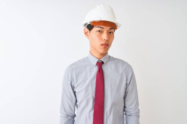 Kravat ve kask takan Çinli mimar, izole edilmiş beyaz arka planda duruyor. Yüzünde ciddi bir ifadeyle rahatlamış. Basit ve doğal bir şekilde kameraya bakıyorsun..