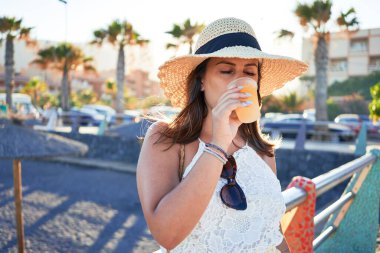 Genç ve güzel bir kadın gülümseyerek mutlu bir yaz tatili geçiriyor taze buzlu içecek içiyor.