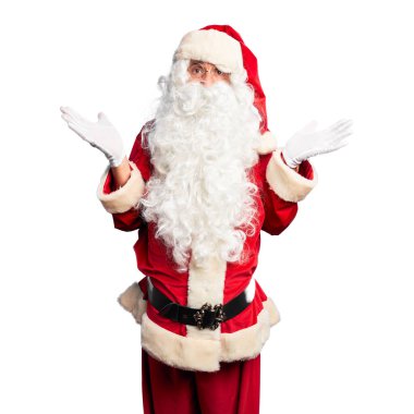 Orta yaşlı yakışıklı adam, Noel Baba kostümü ve sakal takmış, hiçbir şeyden habersiz, elleri ve elleri havada, kafası karışmış bir şekilde duruyor. Şüphe kavramı.