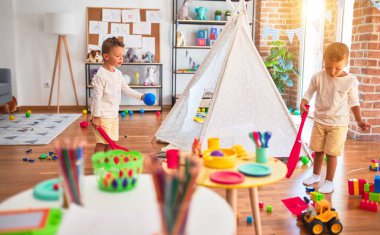 Anaokulunda bir sürü oyuncakla oynayan sevimli sarışın ikizler.