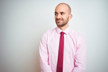 Soyutlanmış arka planda pembe kravat takan genç bir iş adamı yüzünde gülümseme, doğal bir ifade ile yan yana bakıyor. Kendinden emin gülen.