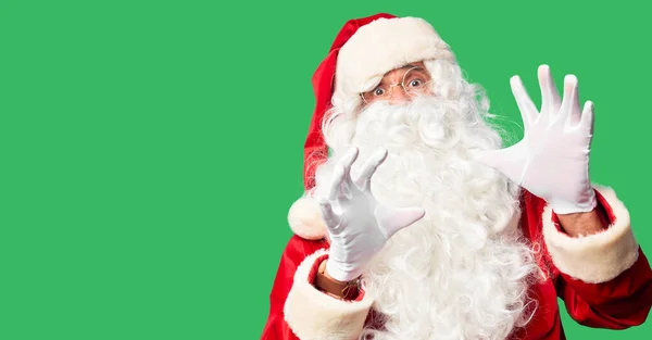 中年英俊男子 身穿圣诞老人服装 蓄着胡子 站在那里 害怕而害怕 用恐惧的表情 用手停止手势 震惊地大叫 恐慌的概念 — 图库照片