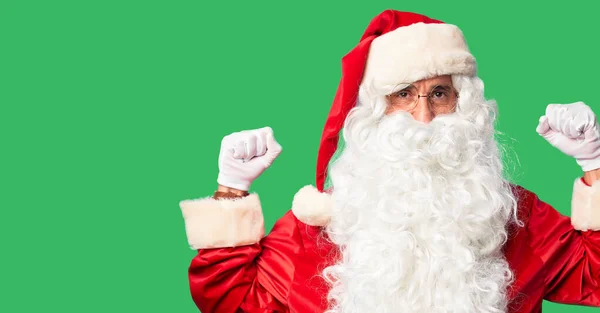 中年男子 身穿圣诞老人服装 蓄着胡子 站在那里 露出臂膀肌肉 露出自豪的笑容 健康概念 — 图库照片
