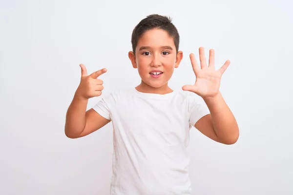 自信を持って幸せな笑顔ながら 孤立した白い背景に立ってカジュアルなTシャツを身に着けている美しい子供の男の子は指の番号7で見上げと指摘 — ストック写真