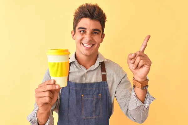 Joven Barista Guapo Con Delantal Sosteniendo Café Sobre Fondo Amarillo — Foto de Stock