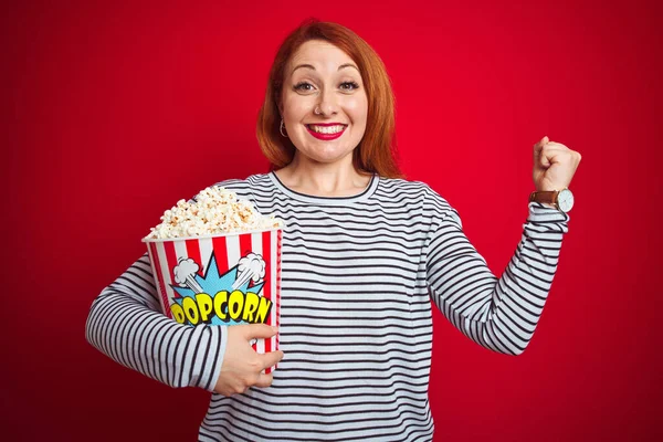 Mladý Krásný Ryšavý Žena Jíst Popcorn Přes Červené Izolované Pozadí — Stock fotografie