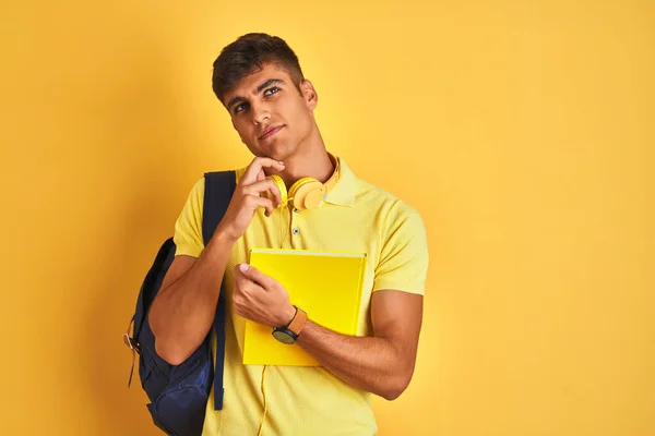 印度学生头戴背负式耳机 背对孤立的黄色背景 严肃地思考问题 非常混乱的想法 — 图库照片