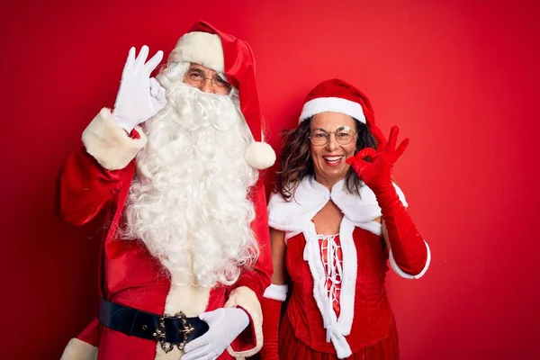 Paar Mittleren Alters Weihnachtsmannkostüm Und Brille Über Isoliertem Rotem Hintergrund — Stockfoto