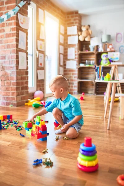 年轻的高加索小孩在幼儿园玩玩具块 学龄前男孩很高兴在游戏室建了一座塔 — 图库照片