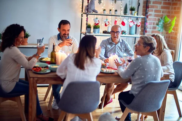 Family and friends dining at home celebrating christmas eve with traditional food and decoration, all sitting on the table together