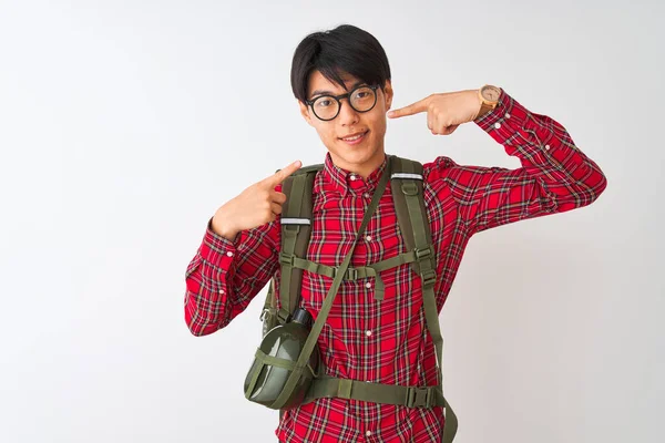Chinese hiker man wearing backpack canteen glasses over isolated white background smiling cheerful showing and pointing with fingers teeth and mouth. Dental health concept.