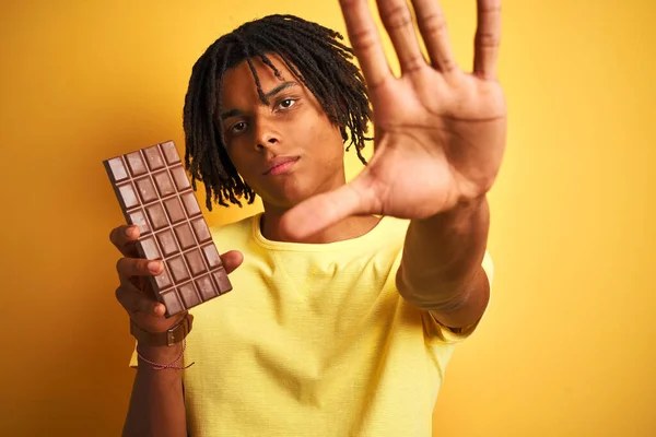 Afro Američan Dredy Jíst Čokoládovou Tyčinku Přes Izolované Žluté Pozadí — Stock fotografie