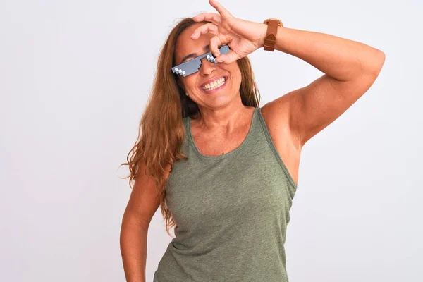 Middle age mature woman wearing thug life sunglasses over isolated background doing ok gesture with hand smiling, eye looking through fingers with happy face.