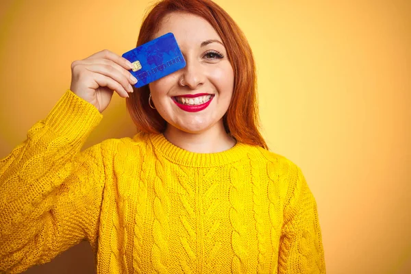Młoda Piękna Ruda Kobieta Trzyma Kartę Kredytową Żółtym Odizolowanym Tle — Zdjęcie stockowe