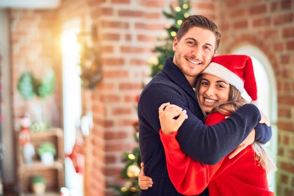 年轻漂亮的夫妇面带微笑 既快乐又自信 在家里站着抱着圣诞树 — 图库照片