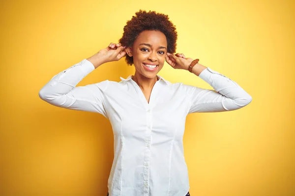 孤立した黄色の背景の上にアフリカ系アメリカ人のビジネス女性指で耳を引く笑みを浮かべて 面白いジェスチャー オーディション問題 — ストック写真