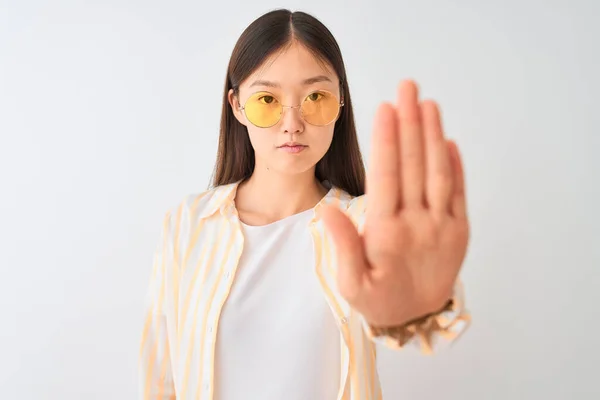 年轻的中国女人 身穿条纹衬衫 戴着眼镜 站在孤立的白色背景上 张开双臂 严肃而自信地做着止步手势 做着防守动作 — 图库照片