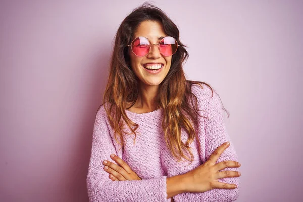 年轻美丽的女人戴着时髦的太阳镜 站在粉色孤立的背景上开心地微笑着 交叉着双臂看着相机 积极的人 — 图库照片
