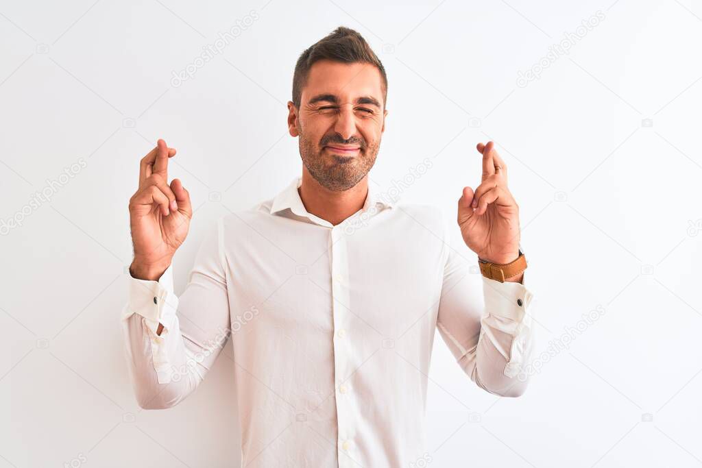 Young handsome business man wearing elegant shirt over isolated background gesturing finger crossed smiling with hope and eyes closed. Luck and superstitious concept.