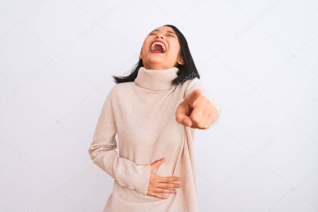 Young chinese woman wearing turtleneck sweater standing over isolated white background laughing at you, pointing finger to the camera with hand over body, shame expression