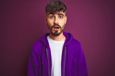 Sarı arka plan üzerinde duran çizgili polo giyen genç adam korku, korku ve heyecan dolu yüz ifadesiyle korkmuş ve şok olmuştu..