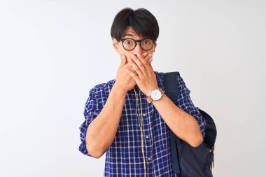 Sırt çantası ve kulaklık takan Çinli bir öğrenci beyaz arka plan üzerine yanlışlıkla ağızlarını kapatarak şok geçirdi. Gizli konsept.