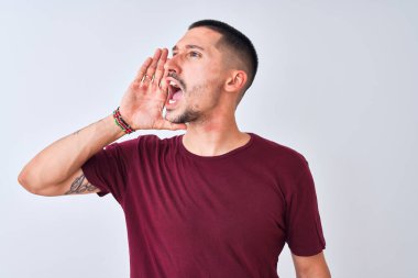 Genç yakışıklı adam izole edilmiş arka planda duruyor ve avazı çıktığı kadar bağırıyor. İletişim konsepti.