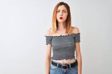 Güzel kızıl saçlı kadın komik yüzü ile yanakları şişirme izole beyaz arka plan üzerinde duran rahat t-shirt giyiyor. Ağız hava ile şişirilmiş, deli ifade.