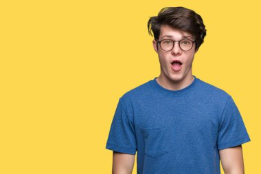 Korkuyor ve şok sürpriz ifade, korku ve heyecan yüz ile izole arka plan üzerinde gözlük takan genç yakışıklı adam.