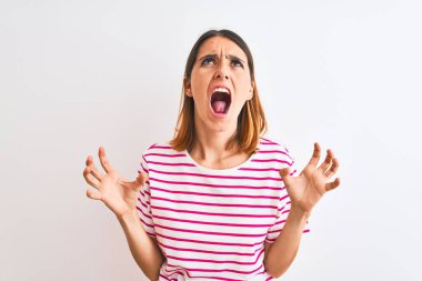 Güzel kızıl saçlı kadın, izole edilmiş arka planda sıradan pembe tişörtler giyiyor deli gibi bağırıyor ve agresif bir ifade ve kollarla bağırıyor. Hayal kırıklığı konsepti.