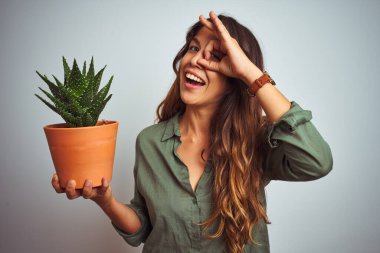 Güzel bir kadın beyaz izole edilmiş arka planda kaktüs tenceresi tutuyor. Gülümsüyor. Tamam işareti yapıyor.