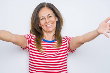 Beyaz soyutlanmış arka planda duran orta yaşlı bir kadın kucaklanmak için kollarını açmış gülümseyen kameraya bakıyor. Mutluluğu kucaklayan neşeli bir ifade..